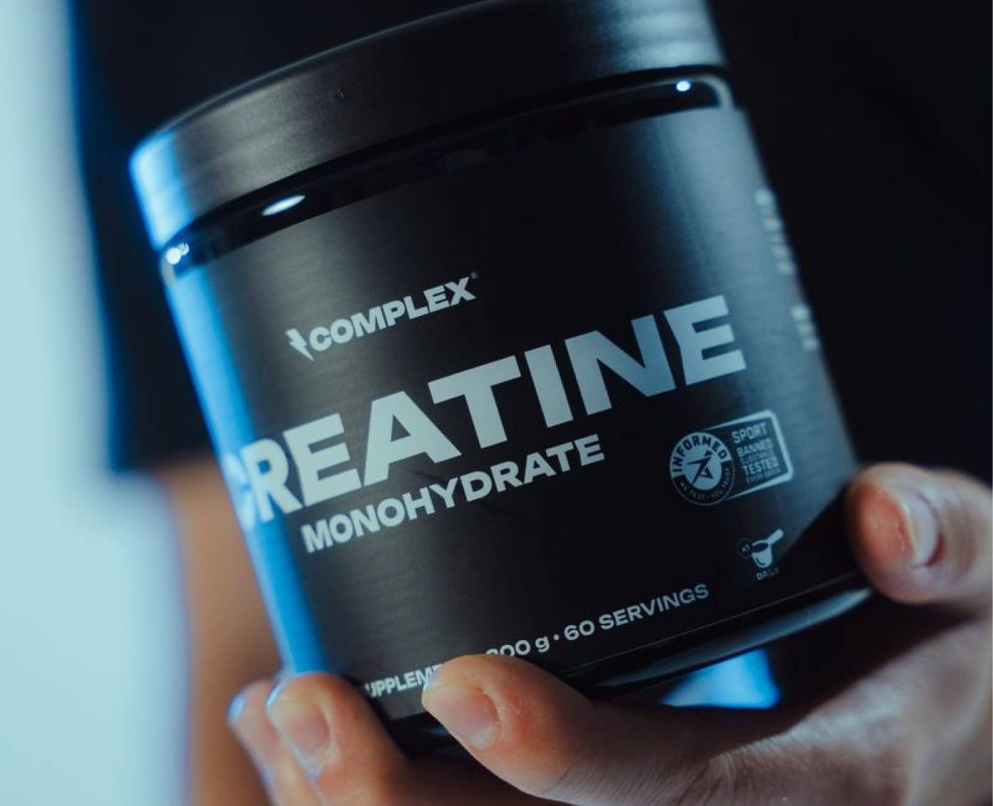 Hand holding a Complex Creatine Monohydrate tub