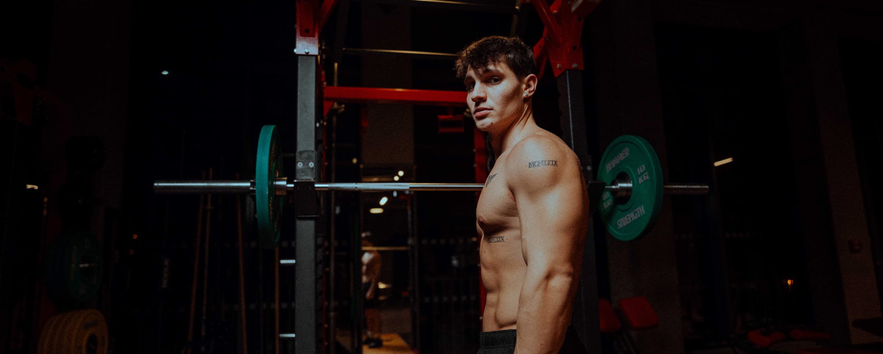 Athlete at a barbell rack in a red-lit gym